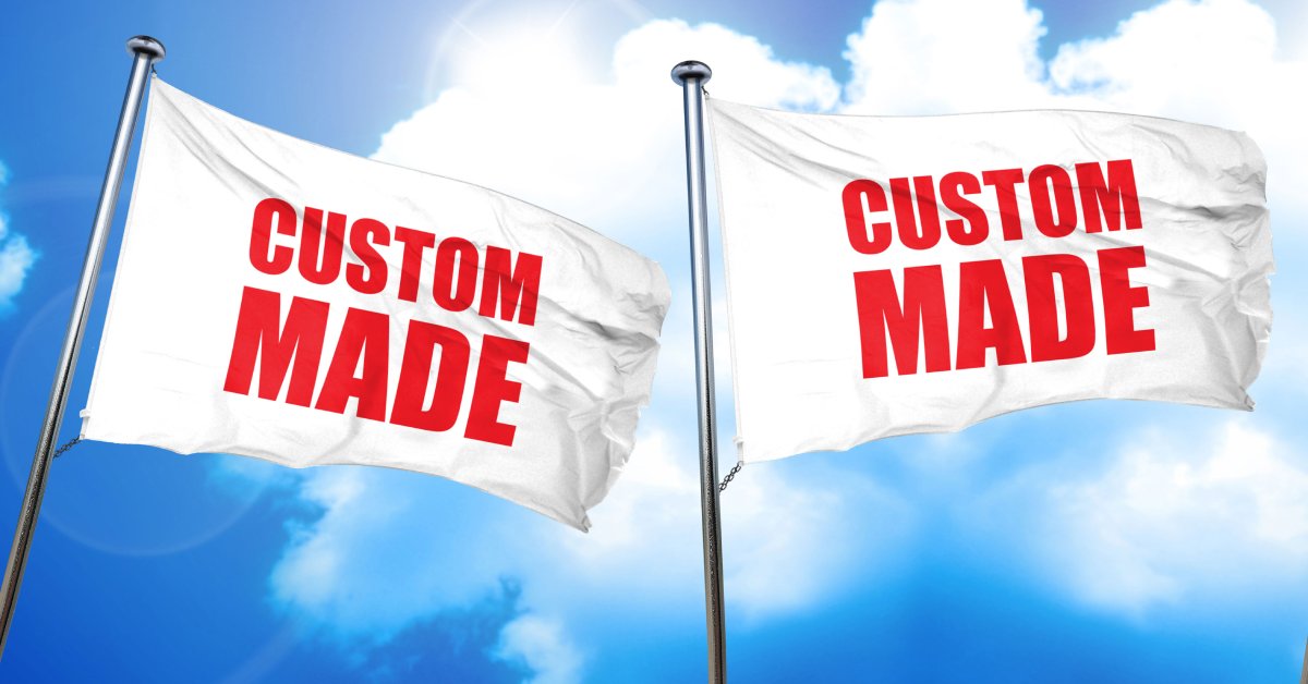 Three white flags with red lettering that each read "CUSTOM MADE" against a blue sky backdrop and white clouds.